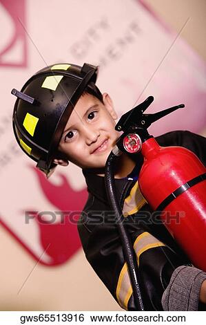 Stock Photograph - Portrait of a boy dressed as a firefighter and holding a fire extinguisher. Fotosearch