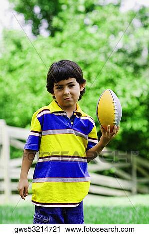 Stock Image - Portrait of a boy holding a rugby ball. Fotosearch
