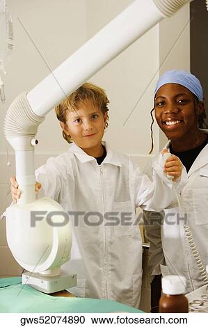 Portrait of a boy imitating a doctor and operating an X-Ray machine with a female doctor standing beside him View Large Photo Image Stock Image - Portrait of a boy imitating a doctor and operating an X-Ray machine with a female doctor standing beside him. Fotosearch