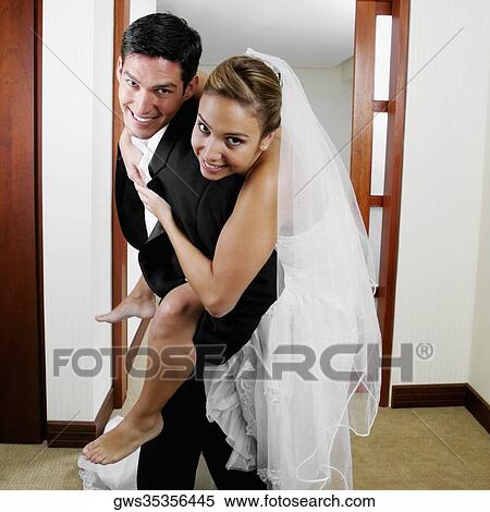 Stock Photography - Portrait of a bride riding piggyback on her groom. Fotosearch