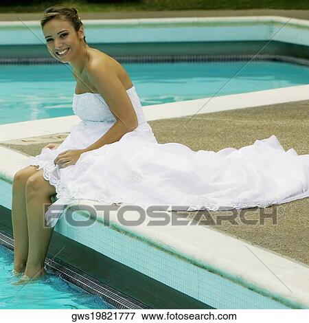 Stock Photo - Portrait of a bride sitting a the poolside and smiling. Fotosearch
