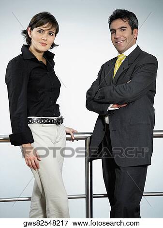 Stock Photo - Portrait of a businessman and a businesswoman standing near a railing. Fotosearch