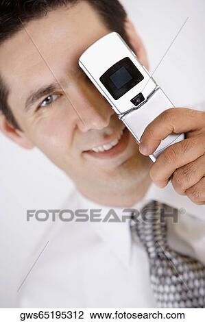 Portrait of a businessman covering his one eye with a mobile phone View Large Photo Image Stock Image - Portrait of a businessman covering his one eye with a mobile phone. Fotosearch