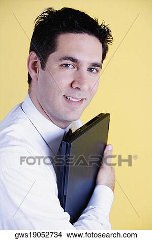 Picture - Portrait of a businessman holding a laptop and smiling. Fotosearch