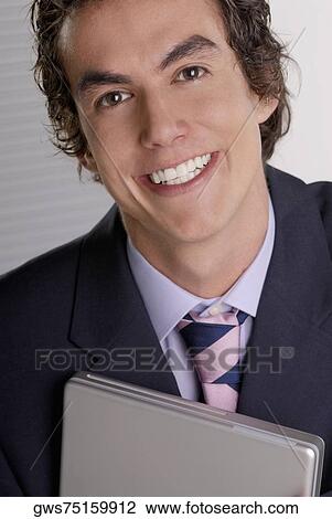 Portrait of a businessman holding a laptop and smiling View Large Photo Image Stock Image - Portrait of a businessman holding a laptop and smiling. Fotosearch