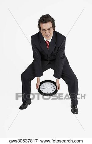 Stock Photo - Portrait of a businessman holding a clock. Fotosearch