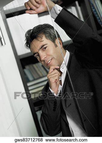 Stock Photo - Portrait of a businessman leaning against a glass door. Fotosearch