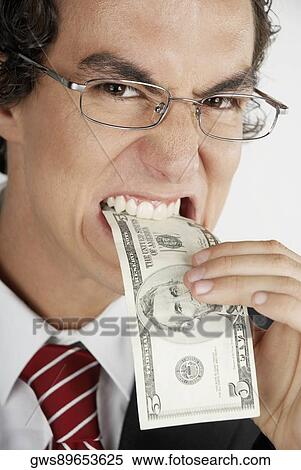 Portrait of a businessman putting a dollar bill into his mouth View Large Photo Image Stock Photography - Portrait of a businessman putting a dollar bill into his mouth. Fotosearch