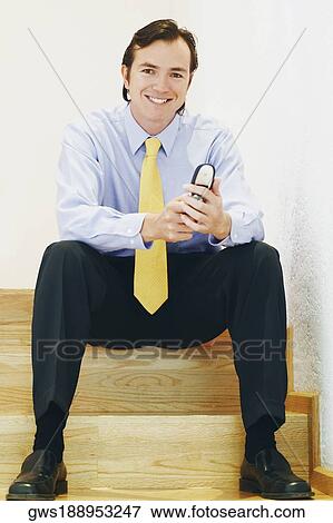 Portrait of a businessman sitting on a staircase and using a mobile phone View Large Photo Image Stock Photo - Portrait of a businessman sitting on a staircase and using a mobile phone. Fotosearch