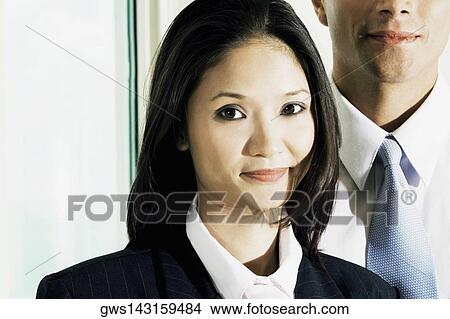 Portrait of a businesswoman and a businessman standing behind her View Large Photo Image Picture - Portrait of a businesswoman and a businessman standing behind her. Fotosearch