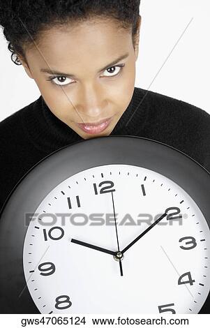 Picture - Portrait of a businesswoman holding a clock. Fotosearch