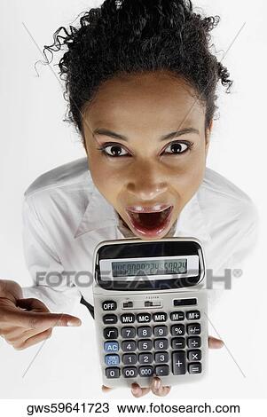 Stock Image - Portrait of a businesswoman pointing at a calculator with her mouth open. Fotosearch