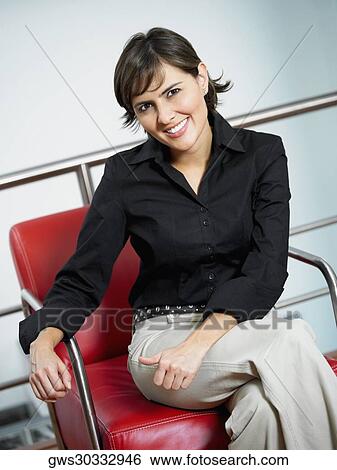 Stock Photograph - Portrait of a businesswoman smiling and sitting in an armchair. Fotosearch