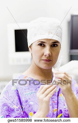 Stock Photo - Portrait of a female doctor holding a syringe. Fotosearch