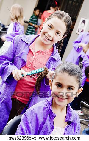 Portrait of a girl combing her sister's hair in a salon View Large Photo Image Stock Photography - Portrait of a girl combing her sister's hair in a salon. Fotosearch