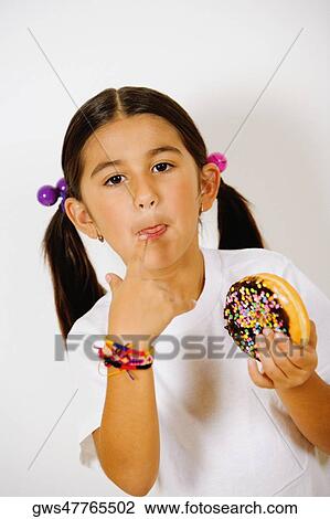 Portrait of a girl holding a donut and licking her finger View Large Photo Image Stock Image - Portrait of a girl holding a donut and licking her finger. Fotosearch
