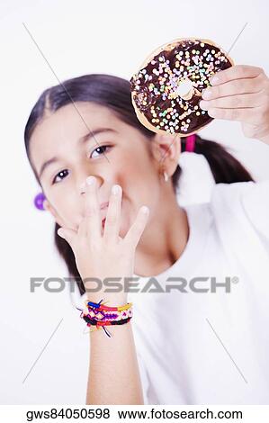 Stock Photo - Portrait of a girl holding a donut and licking her finger. Fotosearch