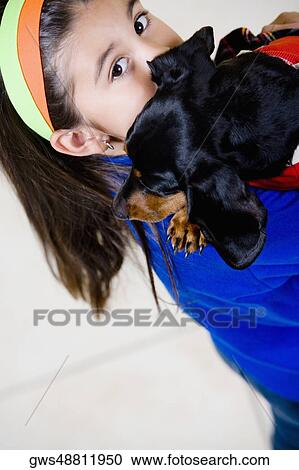 Stock Image - Portrait of a girl holding a puppy on her shoulder. Fotosearch