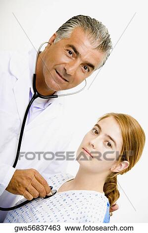Portrait of a male doctor examining a young woman with a stethoscope View Large Photo Image Stock Image - Portrait of a male doctor examining a young woman with a stethoscope. Fotosearch