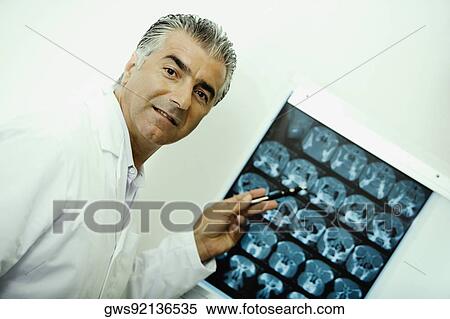 Portrait of a male doctor pointing at an X-Ray View Large Photo Image Stock Photography - Portrait of a male doctor pointing at an X-Ray. Fotosearch