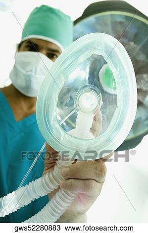 Stock Image - Portrait of a male surgeon holding an oxygen mask. Fotosearch