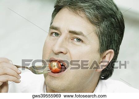 Portrait of a mature man eating a berry with a fork View Large Photo Image Stock Photo - Portrait of a mature man eating a berry with a fork. Fotosearch