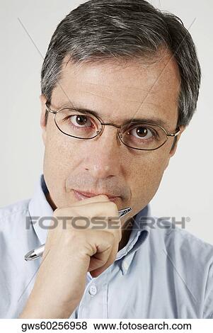 Stock Photo - Portrait of a mature man holding a pen and thinking. Fotosearch
