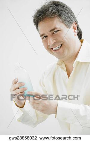 Portrait of a mature man holding a bottle of aftershave and smiling View Large Photo Image Stock Image - Portrait of a mature man holding a bottle of aftershave and smiling. Fotosearch