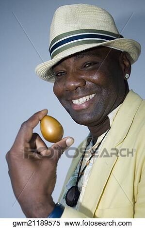 Portrait of a mature man holding a golden egg View Large Photo Image Stock Photography - Portrait of a mature man holding a golden egg. Fotosearch