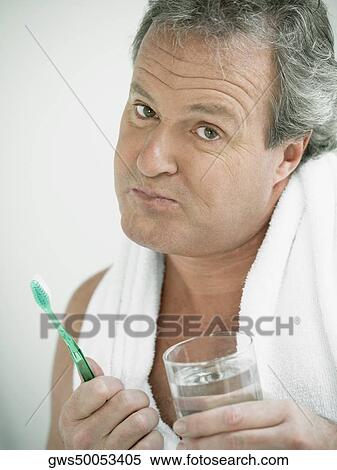 Portrait of a mature man holding a glass of water and a toothbrush View Large Photo Image Stock Photography - Portrait of a mature man holding a glass of water and a toothbrush. Fotosearch