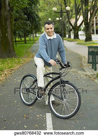 Portrait of a mature man riding a bicycle in the park View Large Photo Image Stock Image - Portrait of a mature man riding a bicycle in the park. Fotosearch