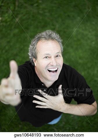 Stock Image - Portrait of a mature man standing in the park and smiling. Fotosearch