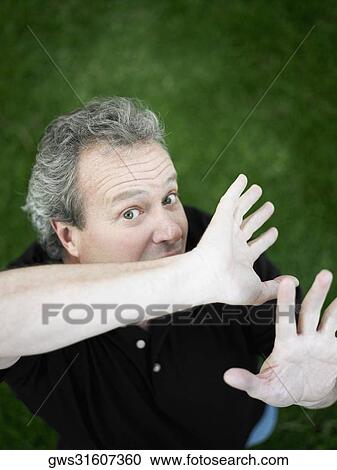 Stock Image - Portrait of a mature man standing in the park. Fotosearch