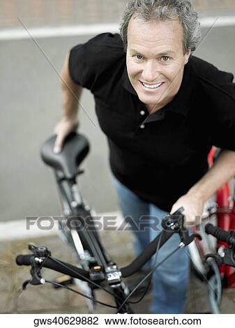 Portrait of a mature man standing with a bicycle and smiling View Large Photo Image Stock Image - Portrait of a mature man standing with a bicycle and smiling. Fotosearch