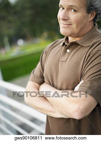 Portrait of a mature man standing with his arms crossed View Large Photo Image Stock Image - Portrait of a mature man standing with his arms crossed. Fotosearch