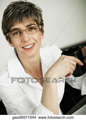 Picture - Portrait of a mature woman holding a cup of coffee and smiling. Fotosearch