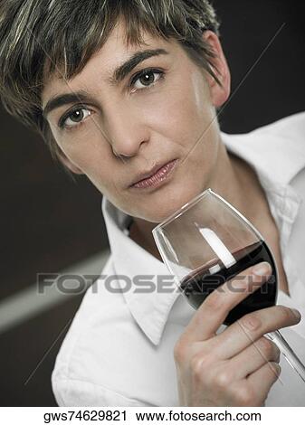 Portrait of a mature woman holding a glass of red wine View Large Photo Image Stock Image - Portrait of a mature woman holding a glass of red wine. Fotosearch