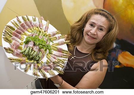 Portrait of a mature woman showing prosciutto wrapped asparagus arranged in a plate View Large Photo Image Stock Image - Portrait of a mature woman showing prosciutto wrapped asparagus arranged in a plate. Fotosearch