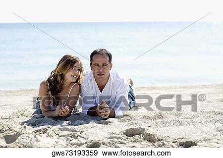 Portrait of a mid adult man and a young woman lying on the beach View Large Photo Image Stock Photo - Portrait of a mid adult man and a young woman lying on the beach. Fotosearch
