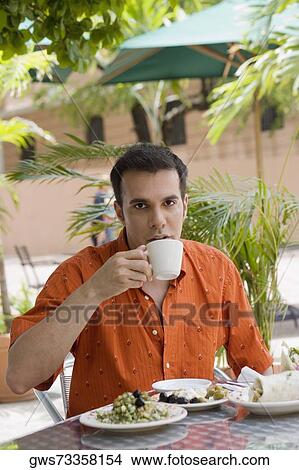 Picture - Portrait of a mid adult man drinking tea at a restaurant. Fotosearch