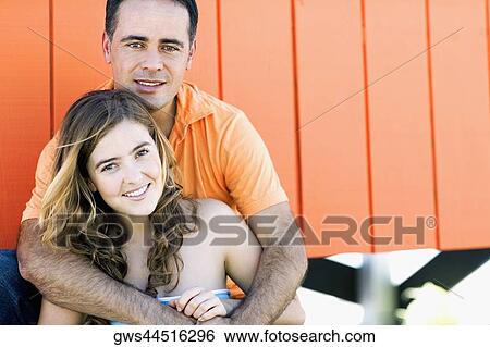 Portrait of a mid adult man embracing a young woman from behind View Large Photo Image Stock Photograph - Portrait of a mid adult man embracing a young woman from behind. Fotosearch
