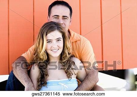 Portrait of a mid adult man embracing a young woman from behind View Large Photo Image Stock Photography - Portrait of a mid adult man embracing a young woman from behind. Fotosearch