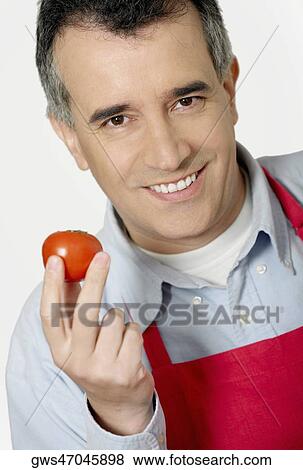 Portrait of a mid adult man holding a tomato and smiling View Large Photo Image Stock Photo - Portrait of a mid adult man holding a tomato and smiling. Fotosearch