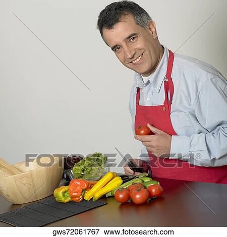 Portrait of a mid adult man holding a kitchen knife and a tomato View Large Photo Image Stock Photo - Portrait of a mid adult man holding a kitchen knife and a tomato. Fotosearch