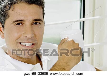Portrait of a mid adult man holding a cup of coffee View Large Photo Image Stock Photography - Portrait of a mid adult man holding a cup of coffee. Fotosearch