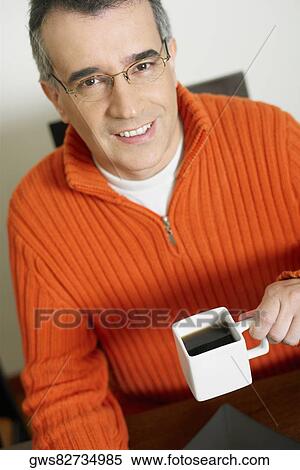 Portrait of a mid adult man holding a cup of coffee View Large Photo Image Stock Photography - Portrait of a mid adult man holding a cup of coffee. Fotosearch