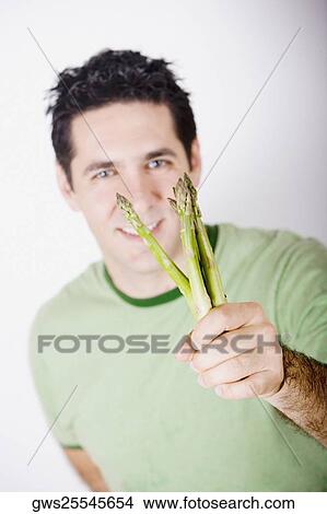 Portrait of a mid adult man holding asparagus and smiling View Large Photo Image Picture - Portrait of a mid adult man holding asparagus and smiling. Fotosearch