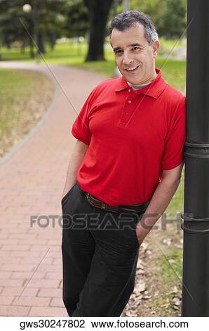 Portrait of a mid adult man leaning against a pole View Large Photo Image Stock Image - Portrait of a mid adult man leaning against a pole. Fotosearch