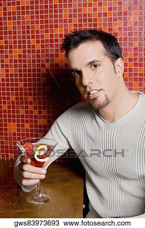 Portrait of a mid adult man sitting at a bar counter and holding a cocktail View Large Photo Image Stock Image - Portrait of a mid adult man sitting at a bar counter and holding a cocktail. Fotosearch