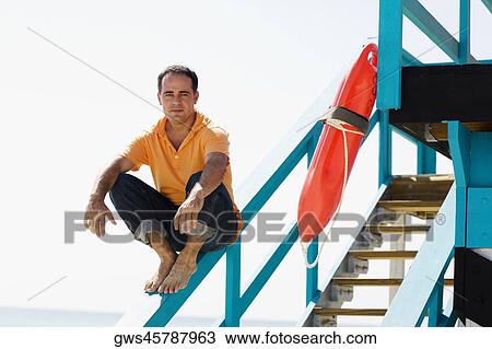Portrait of a mid adult man sitting on the hand rail of a lifeguard hut View Large Photo Image Stock Image - Portrait of a mid adult man sitting on the hand rail of a lifeguard hut. Fotosearch